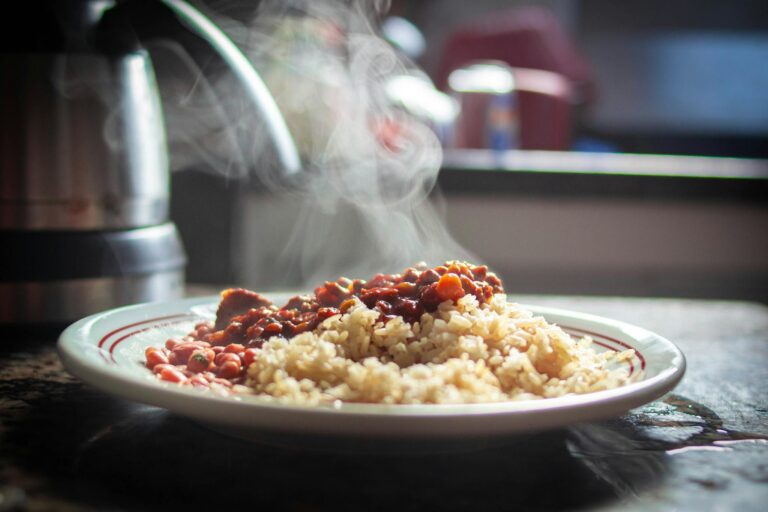 A close-up of steaming rice with beans, captured in warm afternoon light.