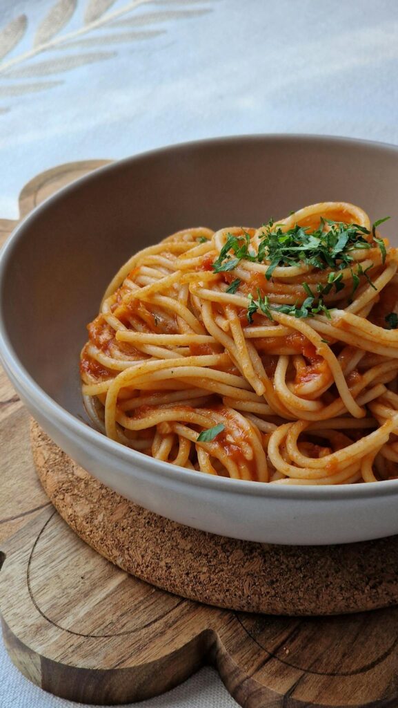 Close-up of a mouthwatering spaghetti dish with tomato sauce and fresh herbs, served in a bowl.